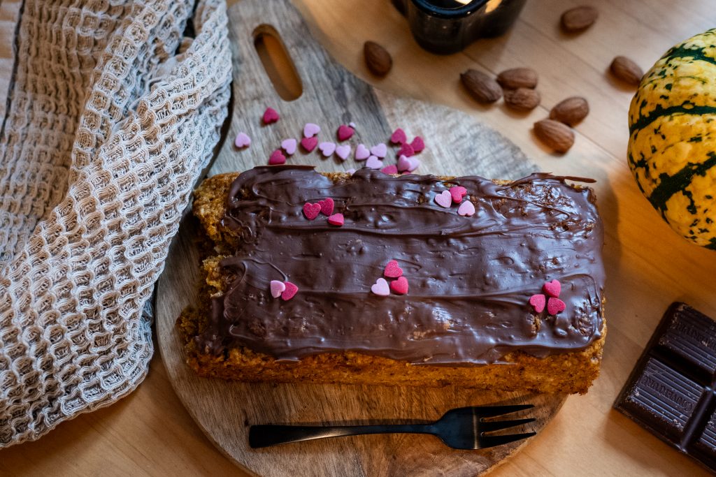 Saftiger veganer Kürbiskuchen mit Kuvertüre und rosa Zuckerherzen